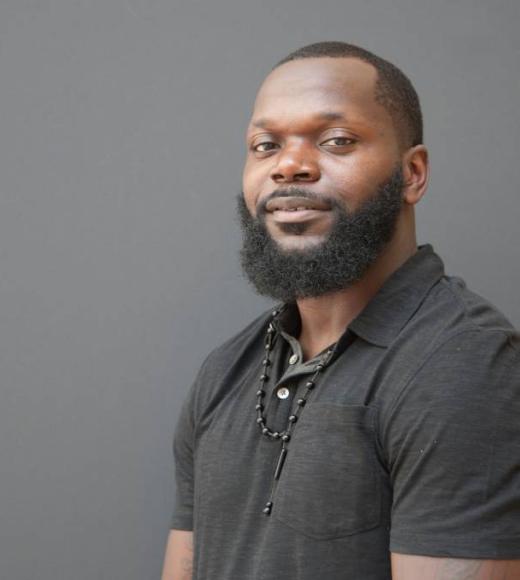 Man wearing a black polo shirt smiling at the camera