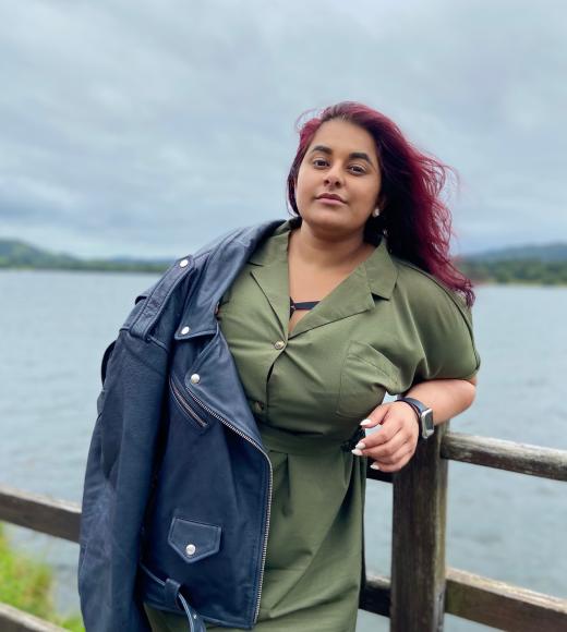 Photo of afshan in nature, leaning against a fence with water in the background