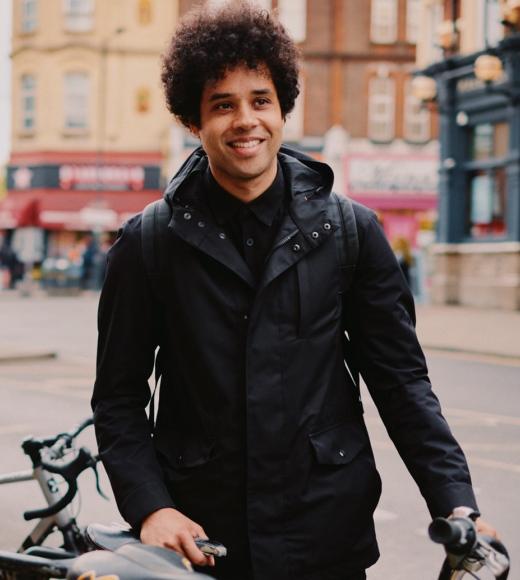 johny pitts, posing with a bike against a city background