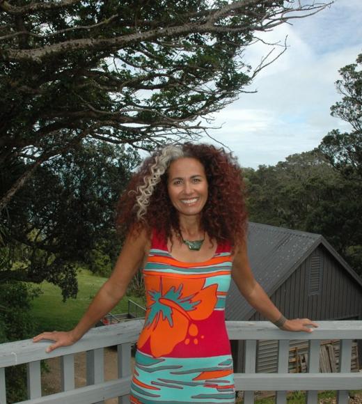 Selina standing in a colorful dress, leaning against a railing